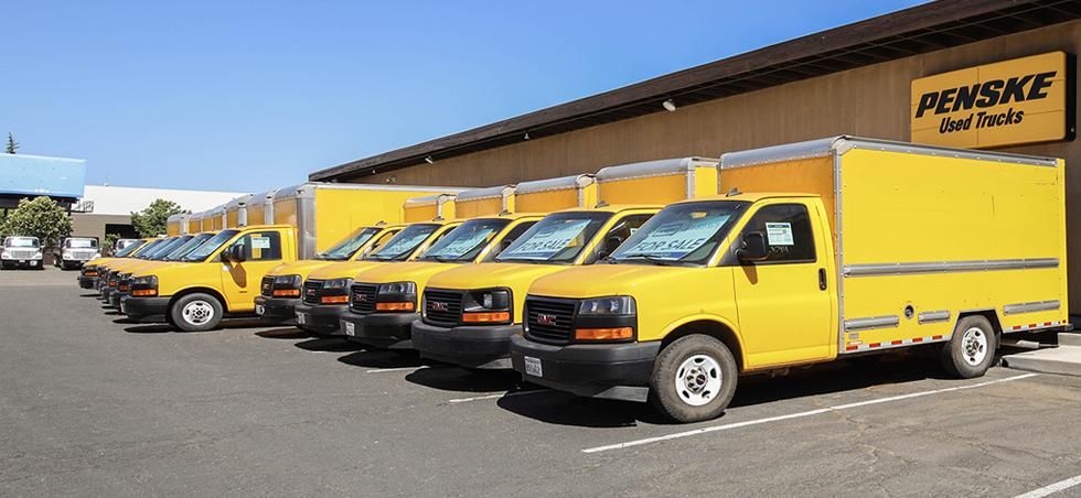 Yellow Penske box trucks lined up in a parking lot.